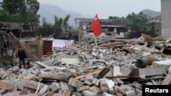 Seorang pria berjalan melewati bendera nasional China yang ditanam di puing-puing pada hari kedua setelah gempa bumi melanda Lushan, Provinsi Sichuan, 21 April 2013, sebagai ilustrasi. (Foto: Reuters)