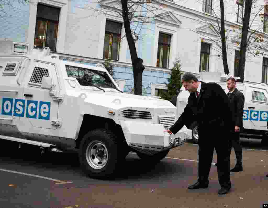 Ukrainian President Petro Poroshenko inspects an armored vehicle at the official handover of 10 armored vehicles to a monitoring team from Organization for Security and Cooperation in Europe on Thursday Nov. 13, 2014.