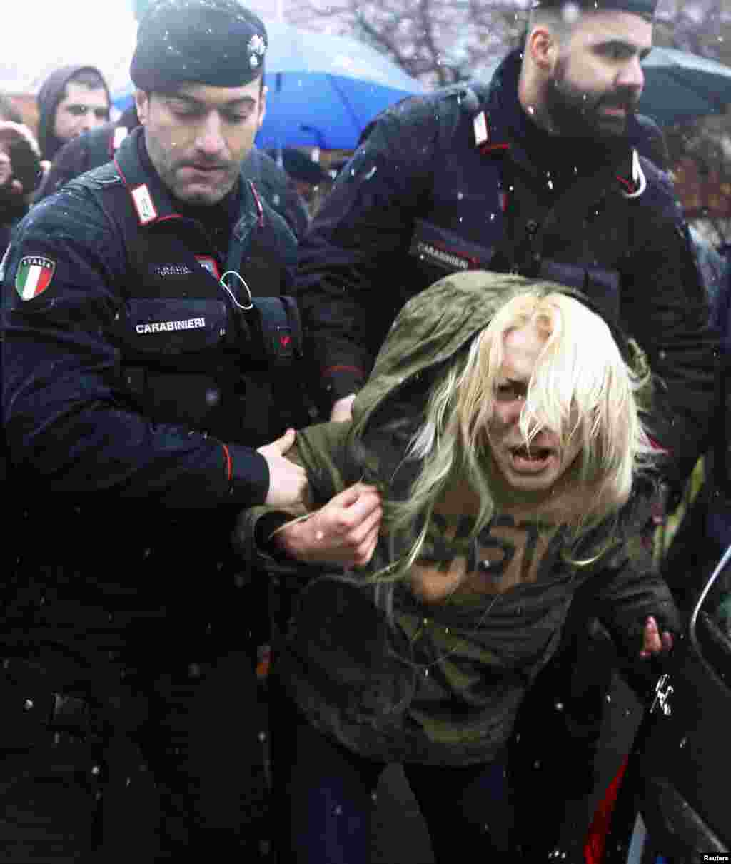 Carabinieri stop a protester from the women's rights organization Femen outside the polling station where former Prime Minister Silvio Berlusconi cast his vote in Milan, Italy, Feb. 24, 2013.