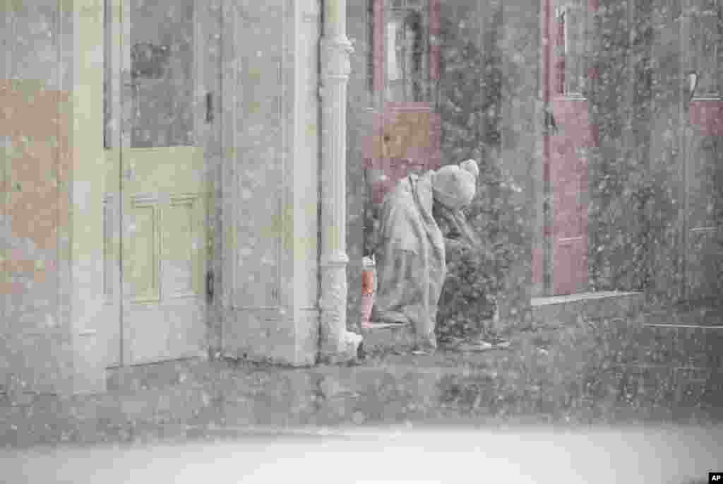 A homeless man sits in a doorway as snow falls in the French Quarter in New Orleans, Louisiana. A rare frigid storm is charging through Texas and the northern Gulf Coast, blanketing New Orleans and Houston with snow, closing highways and grounding nearly all flights.