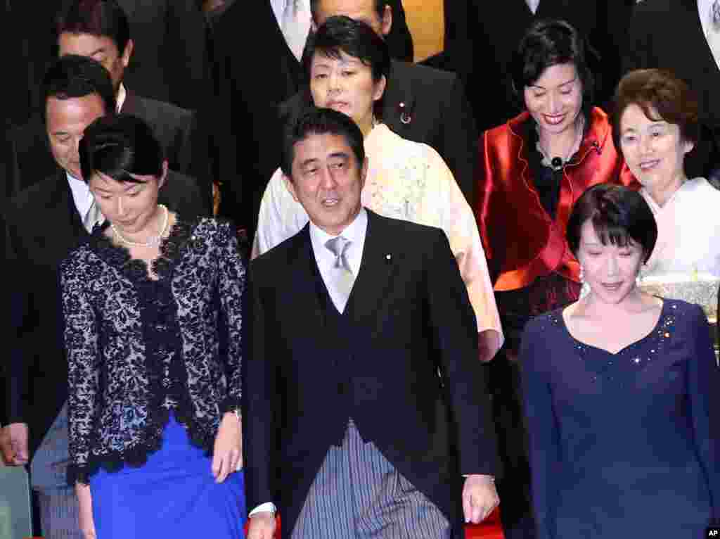 Japan's Prime Minister Shinzo Abe, front row center, and his new Cabinet members, including five women, head for a group photo session following the first Cabinet meeting at the prime minister's official residence in Tokyo.