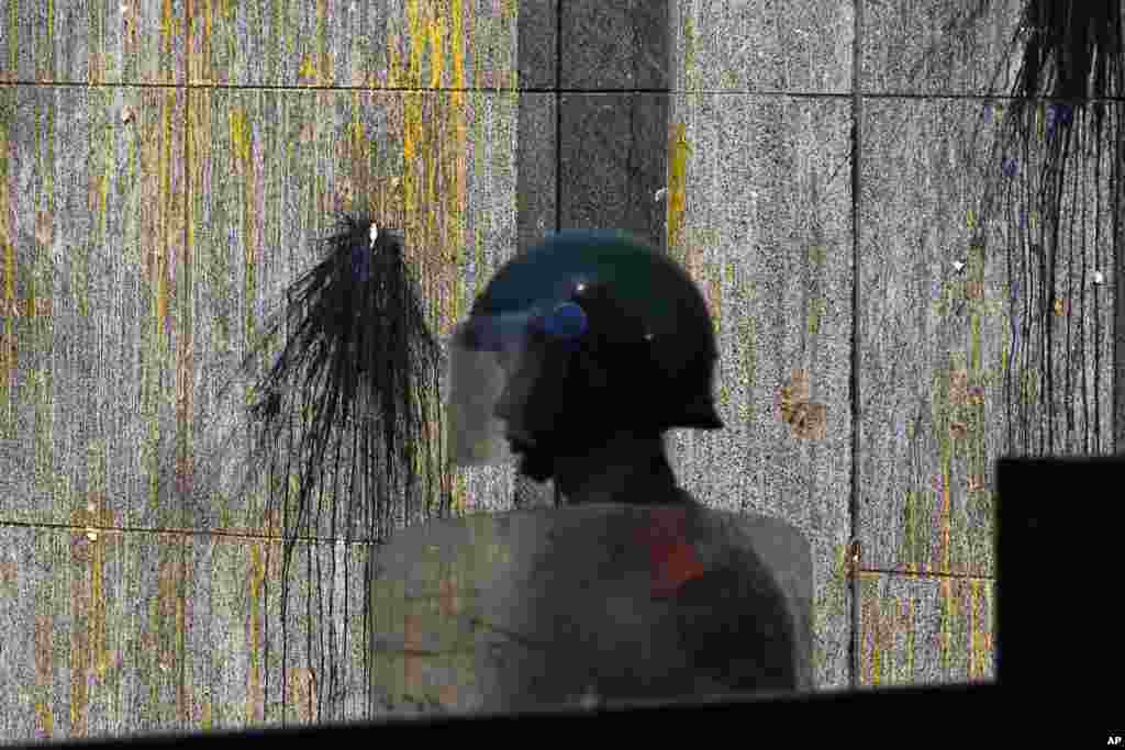 A paramilitary policeman guards an entrance of the Japanese Embassy, eggs and paint splattered on its wall, in Beijing, China, September 16, 2012.
