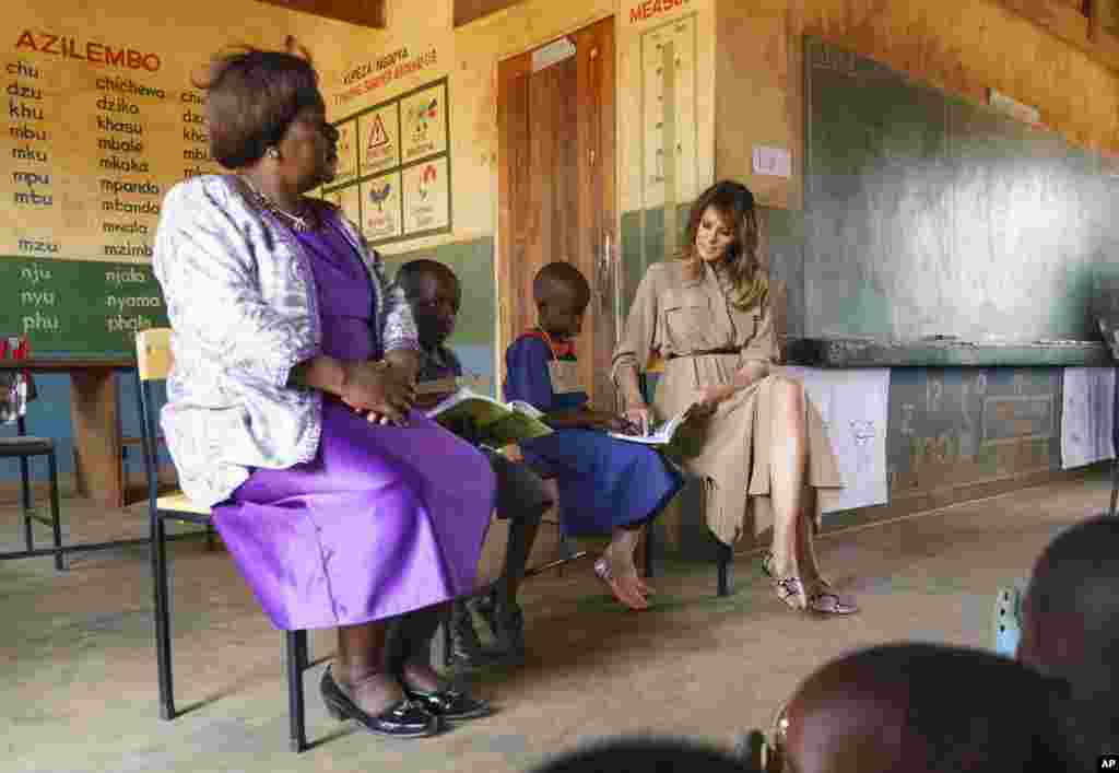 First lady Melania Trump sits with a students and head teacher Maureen Masi during language class as she visits Chipala Primary School, in Lilongwe, Malawi, Oct. 4, 2018.
