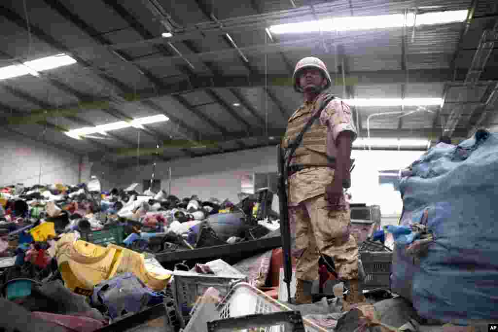 Un soldado mexicano monta guardia entre deshechos para reciclaje en un negocio donde fue encontrada la entrada al túnel.