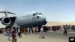 Mamia ya watu wakikimbizana na ndege ya kijeshi ya Marekani kwenye uwanja wa ndege wa Kabul, wakiomba kusafirishwa kutoka nchini humo kufuatia kutekwa kwa mji huo na wapiganaji wa Taliban. 