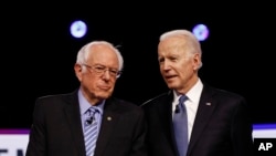 (ពី​ឆ្វេង​មក​ស្តាំ) លោក Bernie Sanders និង​លោក Joe Biden ជជែក​គ្នា​មុន​ពេល​ធ្វើ​ការ​ជជែក​ដេញ​ដោល​ សម្រាប់​តំណែង​បេក្ខជន​ប្រធានាធិបតី​របស់​គណបក្ស​ប្រជាធិបតេយ្យ កាលពី​ថ្ងៃទី២៥ ខែកុម្ភៈ ឆ្នាំ២០២០​ នៅ​ក្នុង​ក្រុង Charleston។