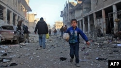 FILE - A Syrian boy runs while carrying bread following a reported airstrike by government forces, in the Syrian town of Binnish, on the outskirts of Idlib.