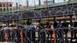 FILE - In this July 16, 2019, file photo, people line up to cross the border into the United States on International Bridge 1, in Nuevo Laredo, Mexico.