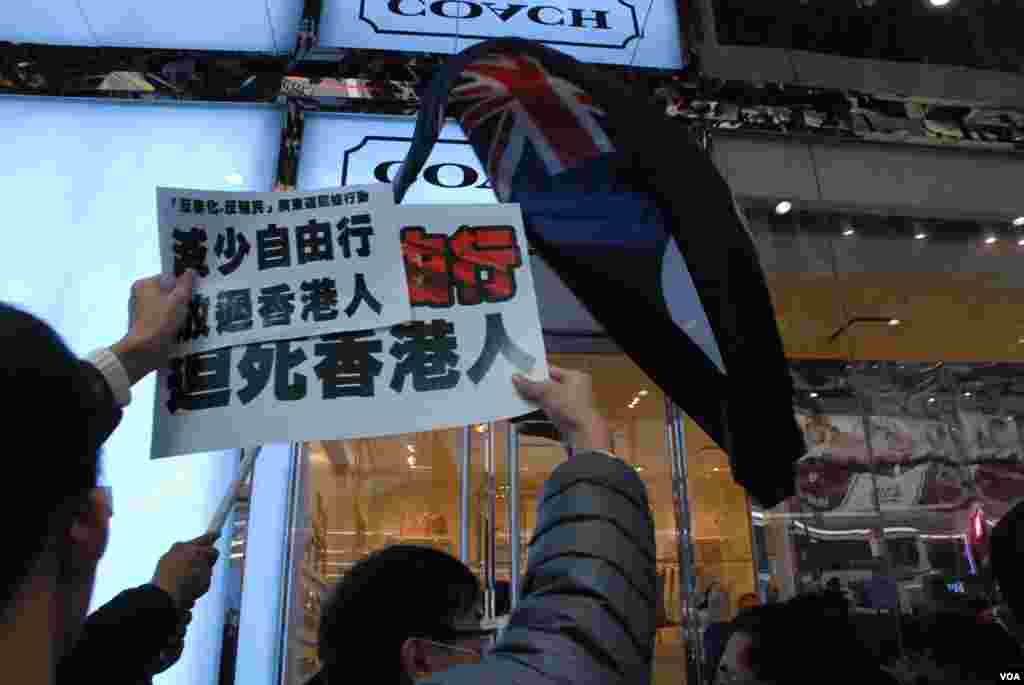 遊行人士對著名店門口高呼反大陸自由行口號,有人做出不雅手勢,店員關上大門保護客人