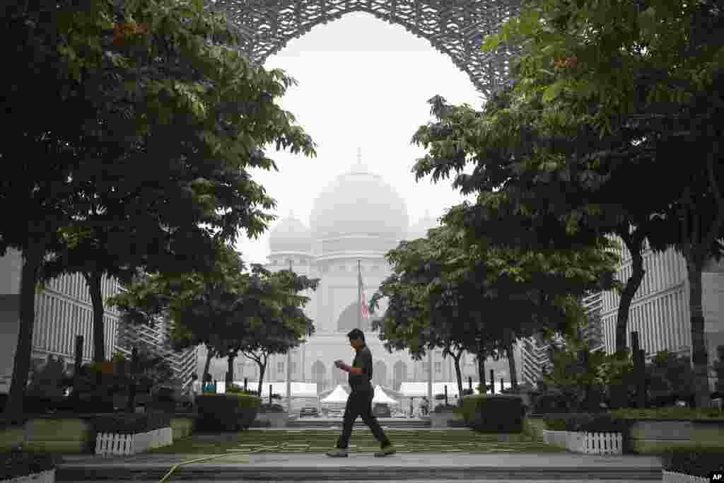 A Malaysian man walks past the Palace of Justice shrouded in haze in Putrajaya, Malaysia. Wildfires caused by illegal land clearing in Indonesia's Sumatra and Borneo islands often spread choking haze to neighboring countries such as Malaysia and Singapore.