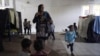 Una mujer hondureña que espera para entrar a Estados Unidos (centro), se peina mientras sus unos niños juegan cerca, en un albergue en Tijuana, México, el 17 de febrero de 2021.