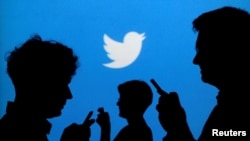 Bayangan orang-orang menggunakan ponsel dengan latar logo Twitter dalam foto ilustrasi, 27 September 2013. (Foto: Reuters)