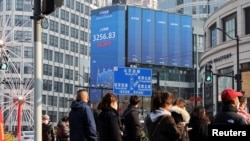 2025年1月21日， 上海街上等待交通號誌的行人與街頭電子廣告看板上顯示的滬深股票指數。