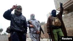 Hombres armados patrullan las calles de Faluya luego de varios días de intensos combates.