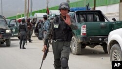 An Afghan policeman prevents journalists from approaching Cure International Hospital in Kabul, Afghanistan, April 24, 2014. 