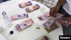 Una mesera cuenta bolívares con los que se pagaron un almuerzo para cuatro personas en un restaurante de Caracas.