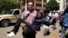 FILE - A journalist rescues a woman injured in a shootout between armed men and police at Nairobi's Westgate shopping mall, Sept. 21, 2013. A new report shows journalists' vulnerability to PTSD after covering extreme violence.