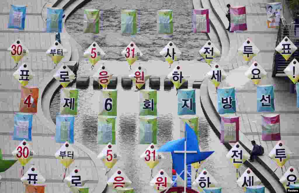 A man (R) sits underneath election campaign placards at the Cheonggye Stream in Seoul, South Korea.
