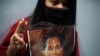 A demonstrator flashes a three-finger salute while holding a picture of Aung San Suu Kyi as Myanmar citizens living in Thailand protest against the military coup, outside Myanmar embassy in Bangkok, Thailand February 4, 2021.