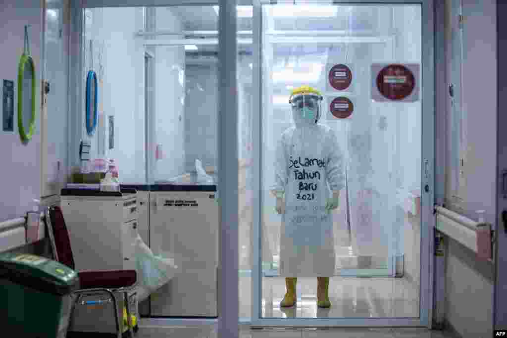 A medical staff wears personal protective equipment (PPE) with the words "Happy New Year 2021" to encourage COVID-19 coronavirus patients while working at the Bogor City Hospital in West Java.
