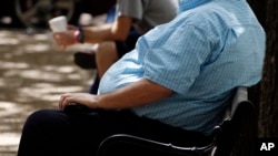 FILE - A heavyset man rests on a bench in Jackson, Miss., Sept. 4, 2014.