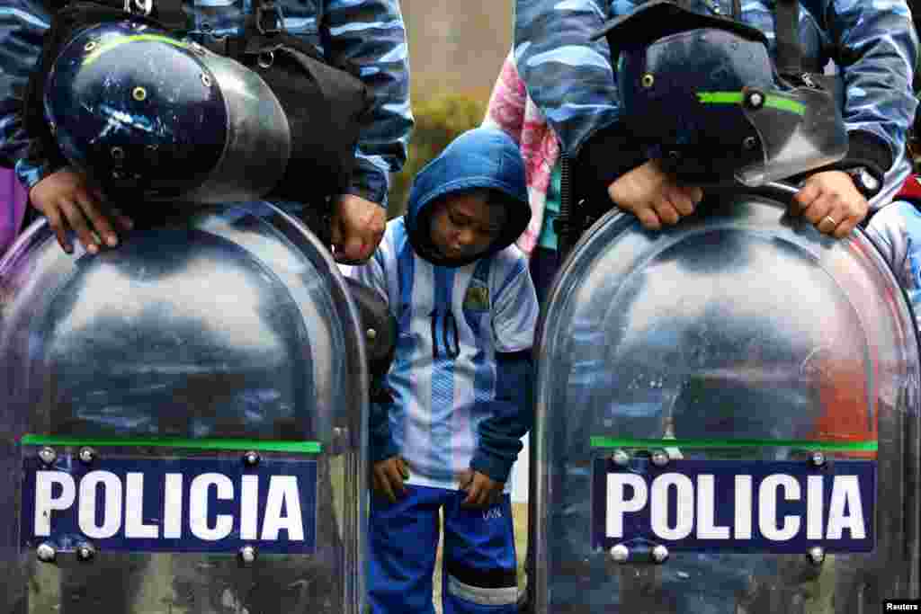 An Argentine fan stands between policemen as they gather to welcome their team outside the Argentine Football Association (AFA) in Buenos Aires after Argentina lost to Germany in their 2014 World Cup final soccer match.