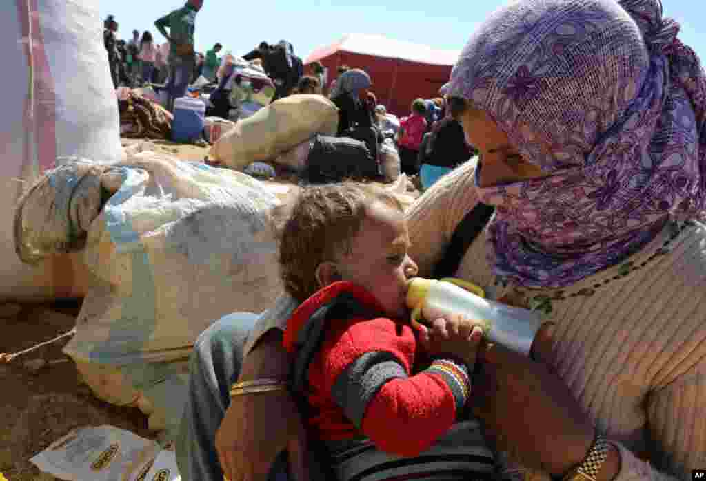 A mother feeds her baby as thousands of new Syrian refugees from Kobani arrive at the Turkey-Syria border crossing of Yumurtalik near Suruc, Turkey, Oct. 1, 2014.