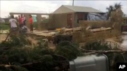 In this image made from a video, people stand near a house damaged by Cyclone Gita in Nuku’alofa, Tonga Tuesday, Feb. 13, 2018. 