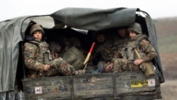 FILE - Ethnic Armenian soldiers sit in a military truck on a road during the withdrawal of troops from the separatist region of Nagorno-Karabakh, Nov. 19, 2020.