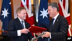 Menteri Pertahanan Inggris Grant Shapps, kiri, dan Menteri Pertahanan Australia Richard Marles bertukar perjanjian kerja sama pertahanan dan keamanan baru di Gedung Parlemen di Gedung Parlemen di Canberra, Kamis, 21 Maret 2024. (Lukas Coch/AAP Image melalui AP)