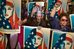 FILE - People carry posters during a rally against President Donald Trump's executive order banning travel from seven Muslim-majority nations, in New York's Times Square, Feb. 19, 2017.