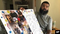Roland Mack holds a poster with pictures and messages made by family members in memory of his sister, Chantee Mack, in District Heights, Md., whose family and co-workers believe, she and several colleagues contracted the disease in their office.