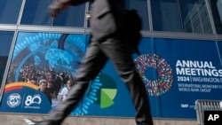 FILE - Seorang anggota delegasi berjalan melewati spanduk IMF, selama Pertemuan Tahunan Bank Dunia/IMF di kantor pusat Dana Moneter Internasional (IMF) di Washington, 21 Oktober 2024.