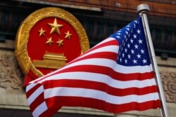 FILE - An American flag is flown next to the Chinese national emblem during a welcome ceremony for visiting U.S. President Donald Trump outside the Great Hall of the People in Beijing, Nov. 9, 2017.