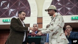 Jenerali Mohammed Hamdan Dagalo na kiongozi wa waandamanaji Ahmad al-Rabiah wakipeana mikono kwenye utiaji saini wa awali wa kushirikiana madaraka