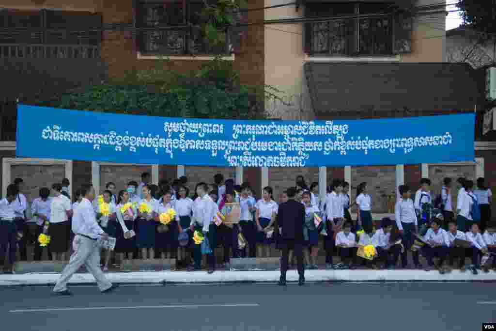 កូនសិស្សឈររង់ចាំក្រោមស្លាកថ្វាយព្រះពរសម្តេចព្រះបរមនាថ នរោត្តម សីហមុនី ក្នុងឱកាសទទួលបានព្រះបរមងារជាកិត្តិយស «ព្រះស្រីលោកធម្មិករាជ» កាលពីថ្ងៃច័ន្ទ ទី៣ ខែមិថុនា ឆ្នាំ២០១៥។