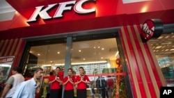 Karyawan KFC menyambut para pengunjung saat pembukaan cabang restoran Kentucky Fried Chicken (KFC) pertama di Ranggon, Myanmar (30/6).