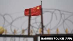 資料照片：中國國旗在新疆喀什南部地區一處建築物的圍欄鐵絲網後飄揚。 （2019年6月4日）