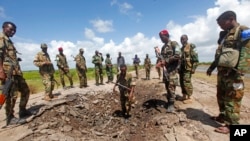 Sejumlah tentara Somalia berdiri di dekat lokasi serangan yang dilancarkan oleh kelompok militan al-Shabab di pangkalan militer tentara Somalia pada 13 Juni 2018. (Foto: AP/Farah Abdi Warsameh)