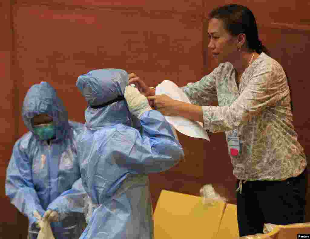 A Philippine health worker assists a colleague with protective suits and equipment during training at the Research Institute for Tropical Medicine hospital in Alabang, Muntinlupa, south of Manila, Oct. 28, 2014.