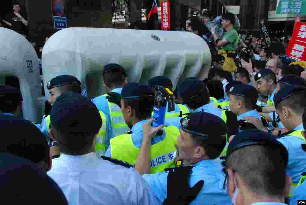 Protesters try to push down the heavy blocks. Police have pepper spray ready.