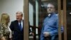 Paul Whelan, a former U.S. Marine, who was arrested in Moscow at the end of last year, right, looks through a cage's glass as his lawyers talk to each other in a court room in Moscow, Russia, Jan. 22, 2019.