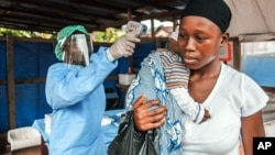 A woman has her temperature taken as part of Ebola prevention, prior to entering the Macauley government hospital in Freetown, Sierra Leone, Jan. 21, 2016. 