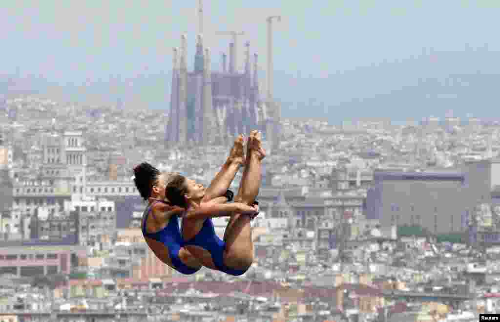 Dua atlet loncat indah Jerman, Julia Stolle dan Maria Kurjo melakukan latihan untuk nomor papan 10m di kolam renang kota Montjuic di Barcelona, sementara di latar belakang tampak katedral Sagrada Familia, salah satu ikon kota Barcelona, Spanyol.