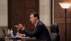 Syria's President Bashar al-Assad speaks as he meets with the Syrian cabinet in Damascus, Syria, in this handout picture released by Sana on March 30, 2021.