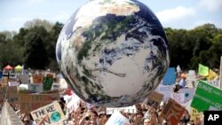 Balon bergambar bola dunia diterbangkan di tengah kerumunan massa, banyak dari mereka siswa sekolah, yang berkumpul di Sydney, Jumat, 20 September 2019, menyerukan tindakan untuk menjaga dunia terhadap perubahan iklim. (AP/Rick Rycroft)