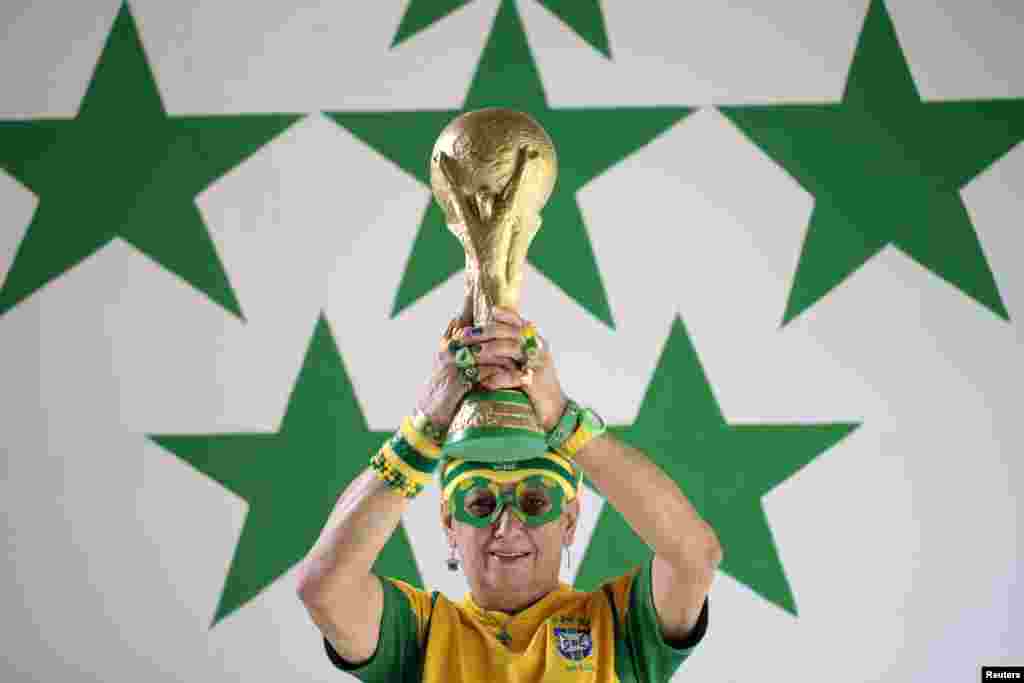 A fã de futebol e acima de tudo fanática pela selecção brasileira, Marilza Guimarães da Silva, de 63 anos, posa para a foto com uma réplica do troféu do Mundial de Futebol, vestida numa das suas diversas indumentárias com as cores do Brasil. Brasília, Maio 27, 2014. REUTERS/Joedson Alves 