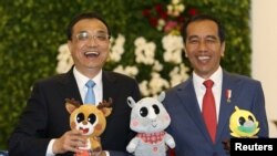 中国总理李克强和印度尼西亚总统佐科·维多多在印尼总统府分享轻松时刻，手持2018年亚运会的吉祥物。（2018年5月7日）