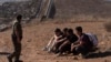 El agente de la Patrulla Fronteriza Gutiérrez pasa junto a cuatro hombres detenidos después de cruzar la frontera ilegalmente en un espacio en dos muros que separan a México de Estados Unidos antes de entregarse, el jueves 23 de enero de 2025, en San Diego. AP