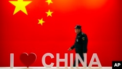 一名保全人員在北京舉行的資訊通訊展覽會上走過「我愛中國」的標語。（2019年10月31日）